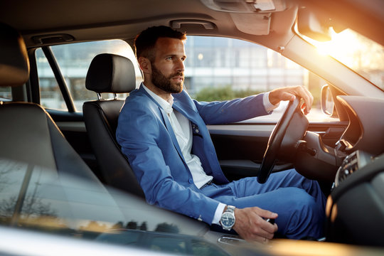 Attractive man in business suit driving car.