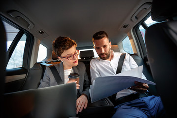 successful business couple working together in back seat of car.