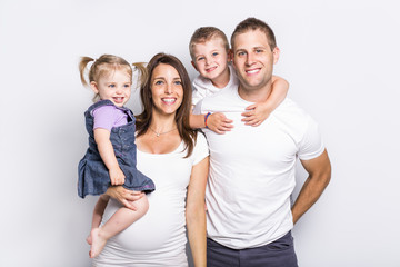 Obraz premium Happy family with two kids on studio gray background