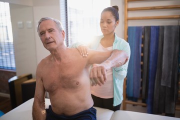 Fototapeta premium Shirtless senior male patient with arms raised receiving neck