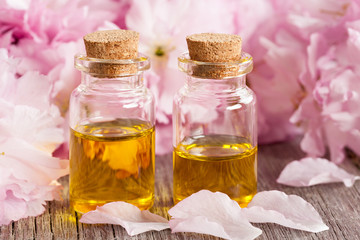 Two bottles of essential oil with pink blossoms