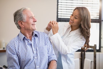 Cheerful female therapist and senior male patient looking at