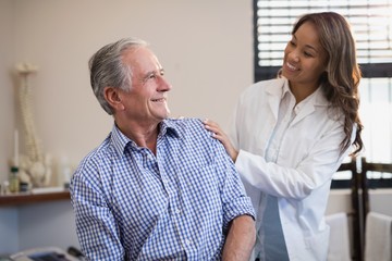 Fototapeta premium Smiling female therapist looking at male patient against window