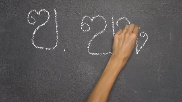 Woman's hand writing Thai letter "ฃ" with white chalk on blackboard