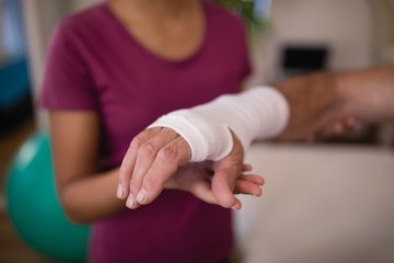 Close-up of senior male patient with bandage on wrist by female