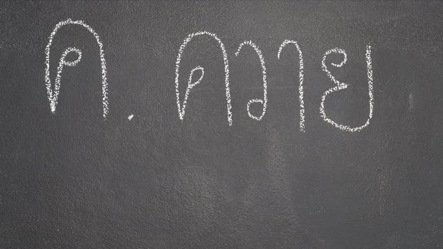 Woman's hand writing Thai letter "ค" with white chalk on blackboard