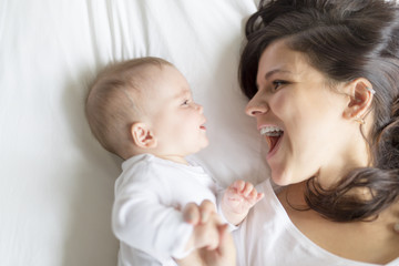 happy loving family. mother playing with her baby in the bedroom.