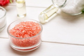Sea salt for spa and bathing and few glass bottles with oil inside on a white wooden table