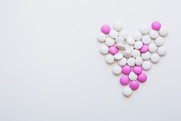 heart shape made of capsule pills on white background
