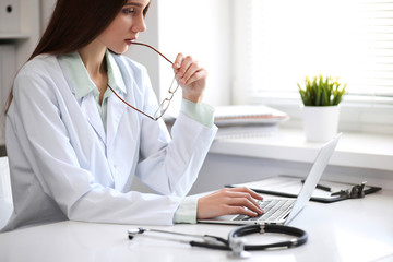 Female doctor brunette sitting  at the table near the window in hospital