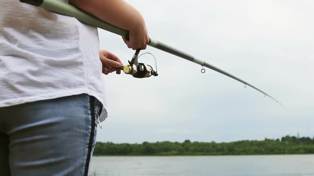 woman spins the reel of the rod and cut the line