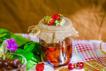 Homemade strawberry jam in glass jar on a table in rustic style. Healthy food for breakfast