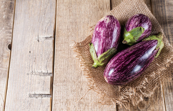 Some eggplants, garlic and red onion on a wooden background