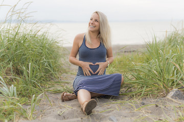 Portrait of a young beautiful blond pregnant woman on the side of the beach