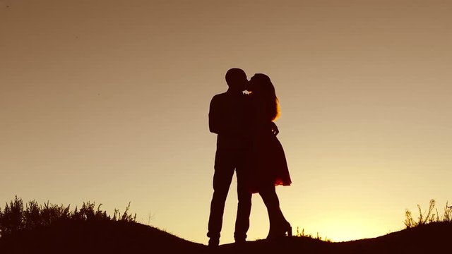 Couple in love kiss walking sunset on silhouette nature slow motion video. Man and woman silhouette of love walk with a dog