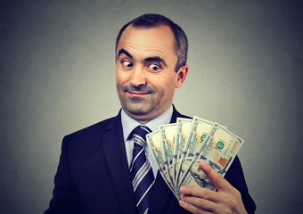 Funny sly business man holding looking at money dollar banknotes