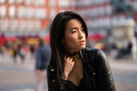 Chinese young and pretty woman in Plaza Mayor of Madrid, Spain, wearing a leather jacket