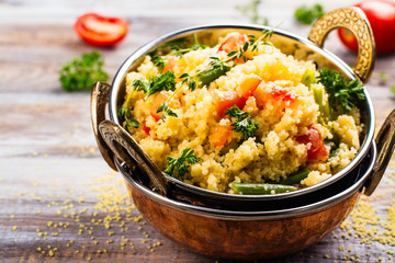 Couscouos Tabbouleh salad with tomatoes and kidney beans in a copper bowl on wooden table