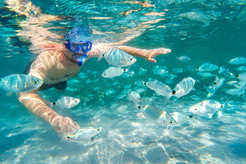 Jonge man snorkelen in onderwater koraalrif op tropisch eiland.