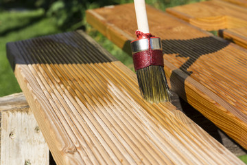 Woman applying protective varnish or wood oil on a wooden boards.