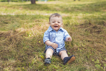 Naklejka na ściany i meble Happiness Baby boy sitting on the grass in field