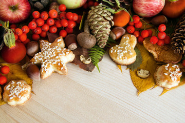 Colorful autumn leaves, mushrooms, rose hips, rowanberry, apples, nuts, cones and cookies on the wooden background. Fall background.