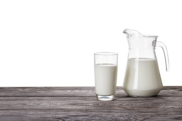 Jug and a glass of milk on a wooden table