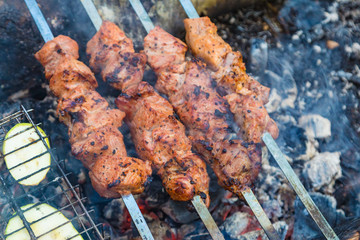 Close up pork meat grilled on skewers. Cooking shashlik in the forest. Grilling pork on coal