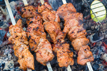 Close up pork meat grilled on skewers. Cooking shashlik in the forest. Grilling pork on coal