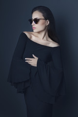 elegant young woman wearing black dress and sunglasses