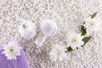 Fototapeta na wymiar Spa. Still life. Herbal balls, a towel and flowers on a background of white pebbles.