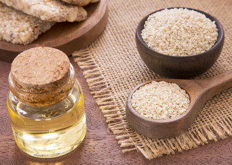 Sesame oil in glass jar and sesame seeds on wooden spoon - Sesamum indicum