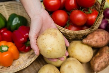 Woman holding fresh potato at vegetable stall