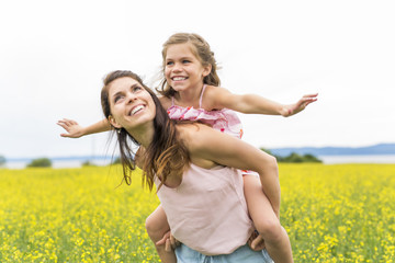 Happy family mother and child daughter embrace on yellow flowers on nature in summer