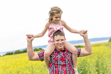 Happy family father and child daughter on yellow flowers on nature in summer