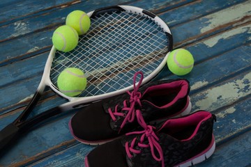 High angle view of black sports shoes by tennis balls and racket - Powered by Adobe