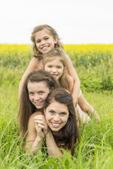 Happy family mother and childs daughter embrace on yellow flowers on nature in summer