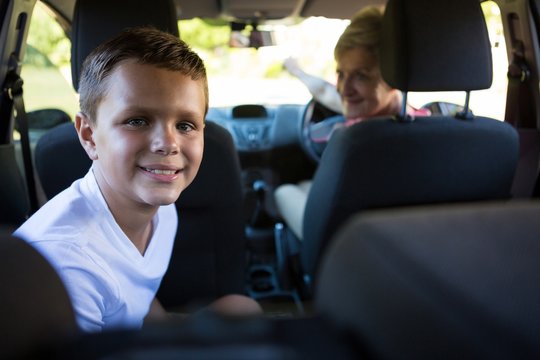 Grandmother driving a car while grandson sitting in the back