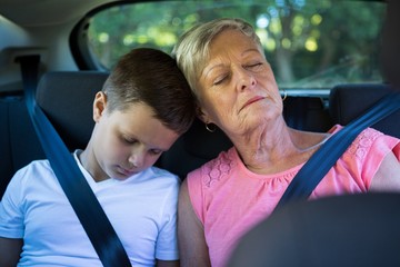 Grandmother and grandson relaxing in the back seat of car - Powered by Adobe