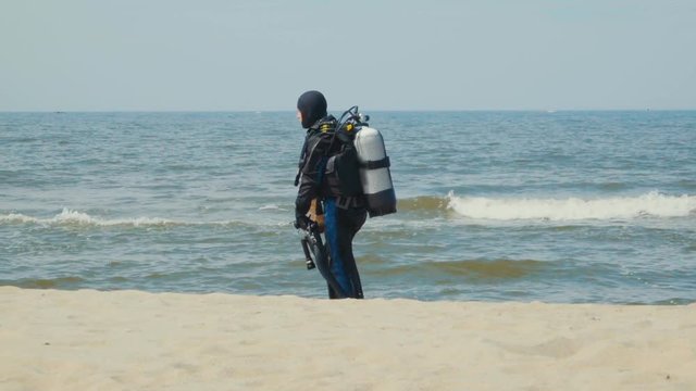 Scuba diver walking back to shore along the sea coast. Slow Motion.