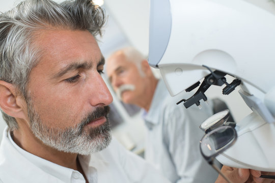 portrait of mid adult male scientist using microscope in laboratory