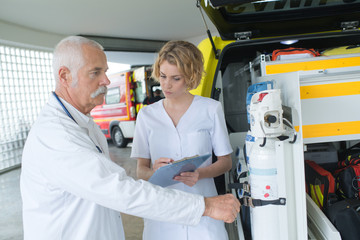 doctor and paramedic or ambulance team reviewing gear at hq