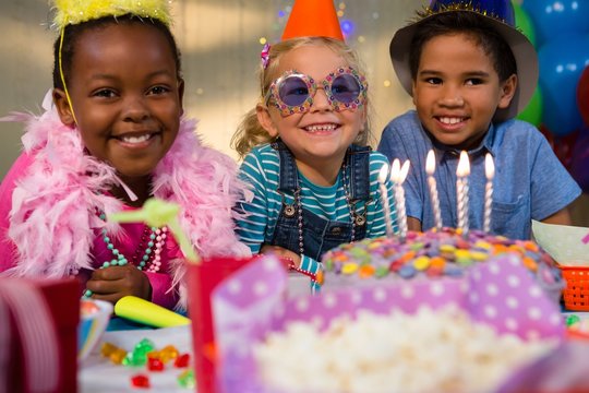 Portrait of happy children by birthday cake