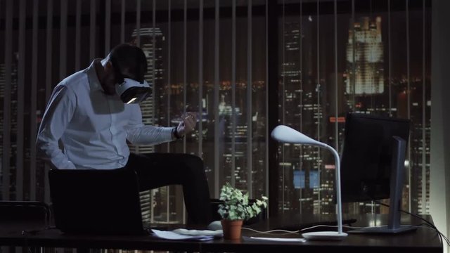 Man in virtual reality headset playing in office at night. The office manager plays the guitar and then the drums.