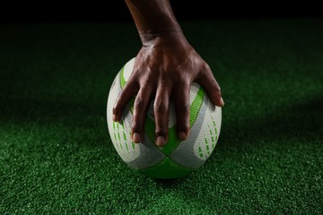 Cropped hand of sportsperson on rugby ball