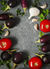Tomatoes, eggplants and garlic over stone texture background. Top view