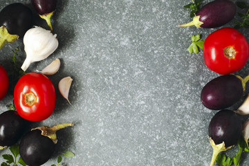 Tomatoes, eggplants and garlic over stone texture background.