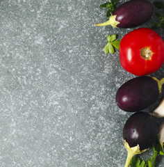 Tomatoes, eggplants and garlic over stone texture background.