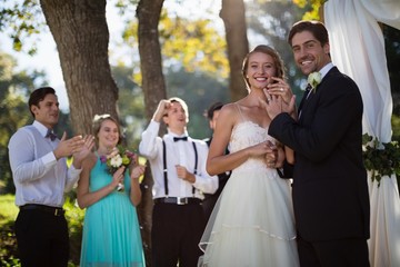 Happy bride and groom showing engagement ring in park