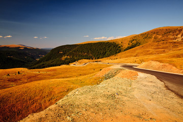 A golden hour wide angle shot of a road in the Transalpina Mountains in Transylvania, Romania